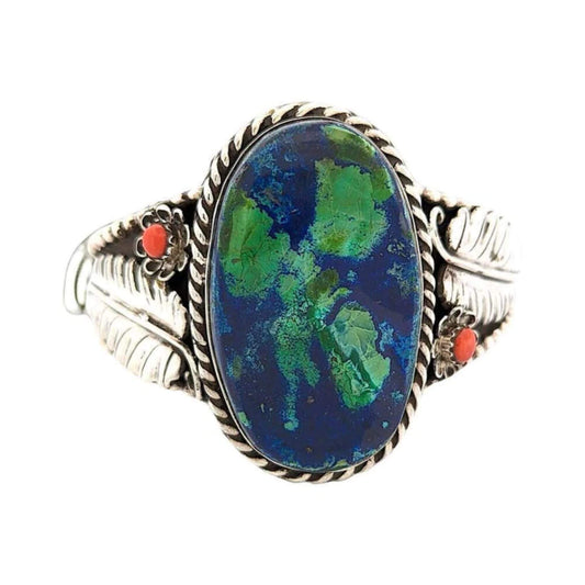 Statement bracelet featuring a bold azurite cabochon with vibrant blue and green hues, floral accents, and a sterling silver cuff.
